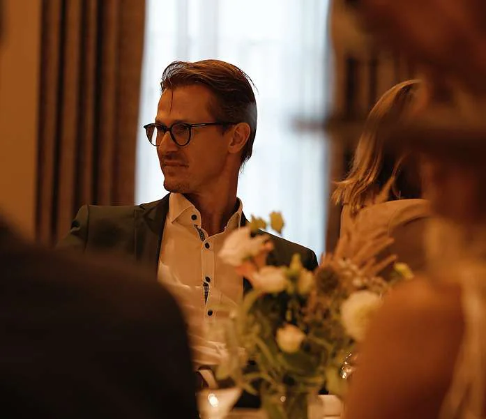 A man in glasses at a formal dinner table