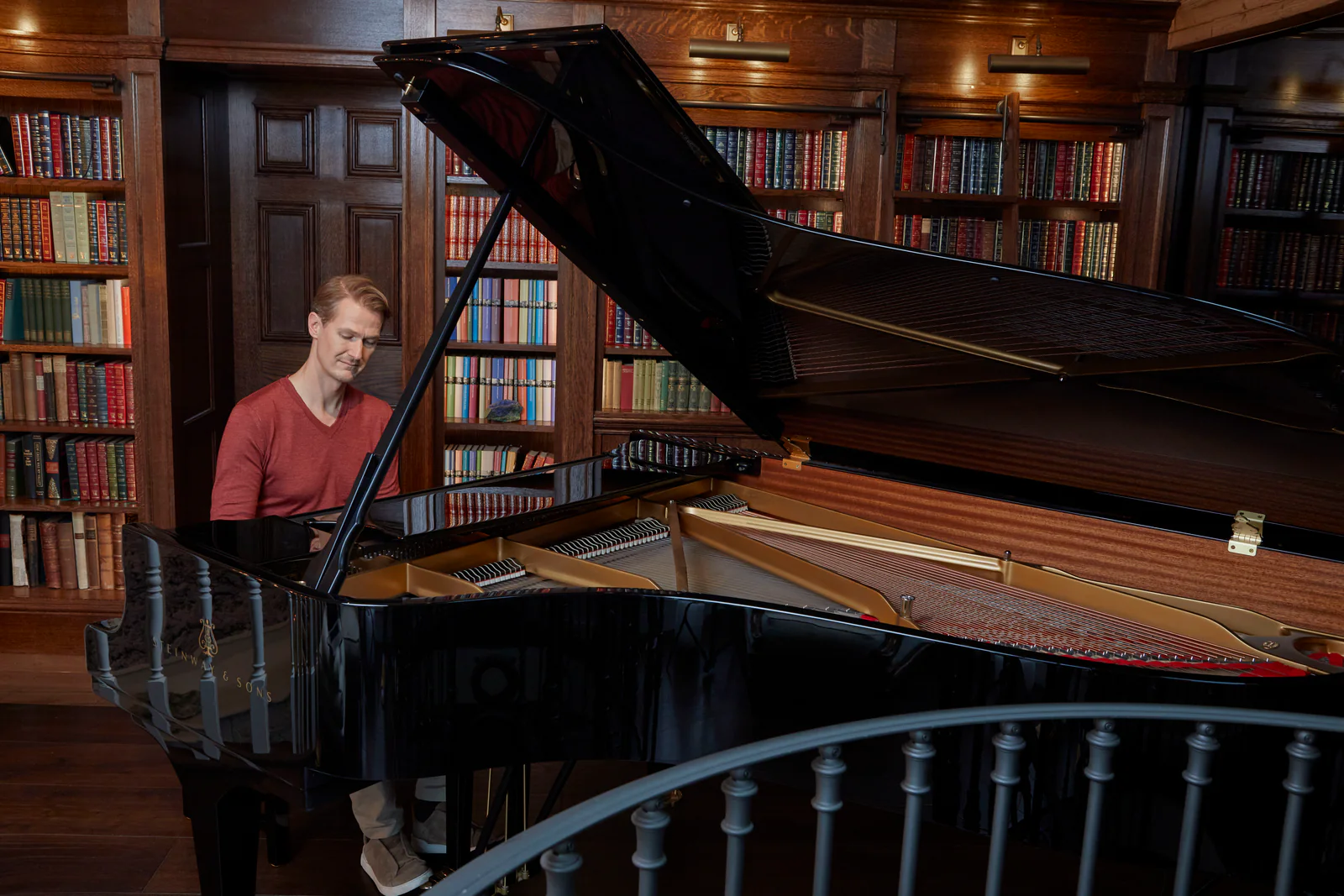 A man playing a grand piano in a library
