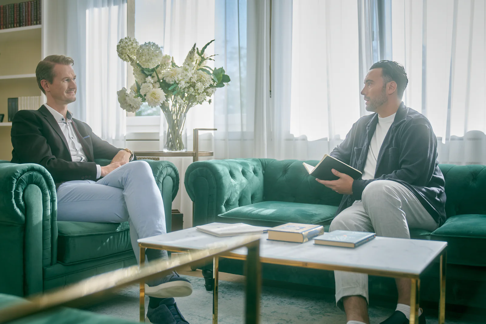 Two men in conversation on a sofa in a bright room