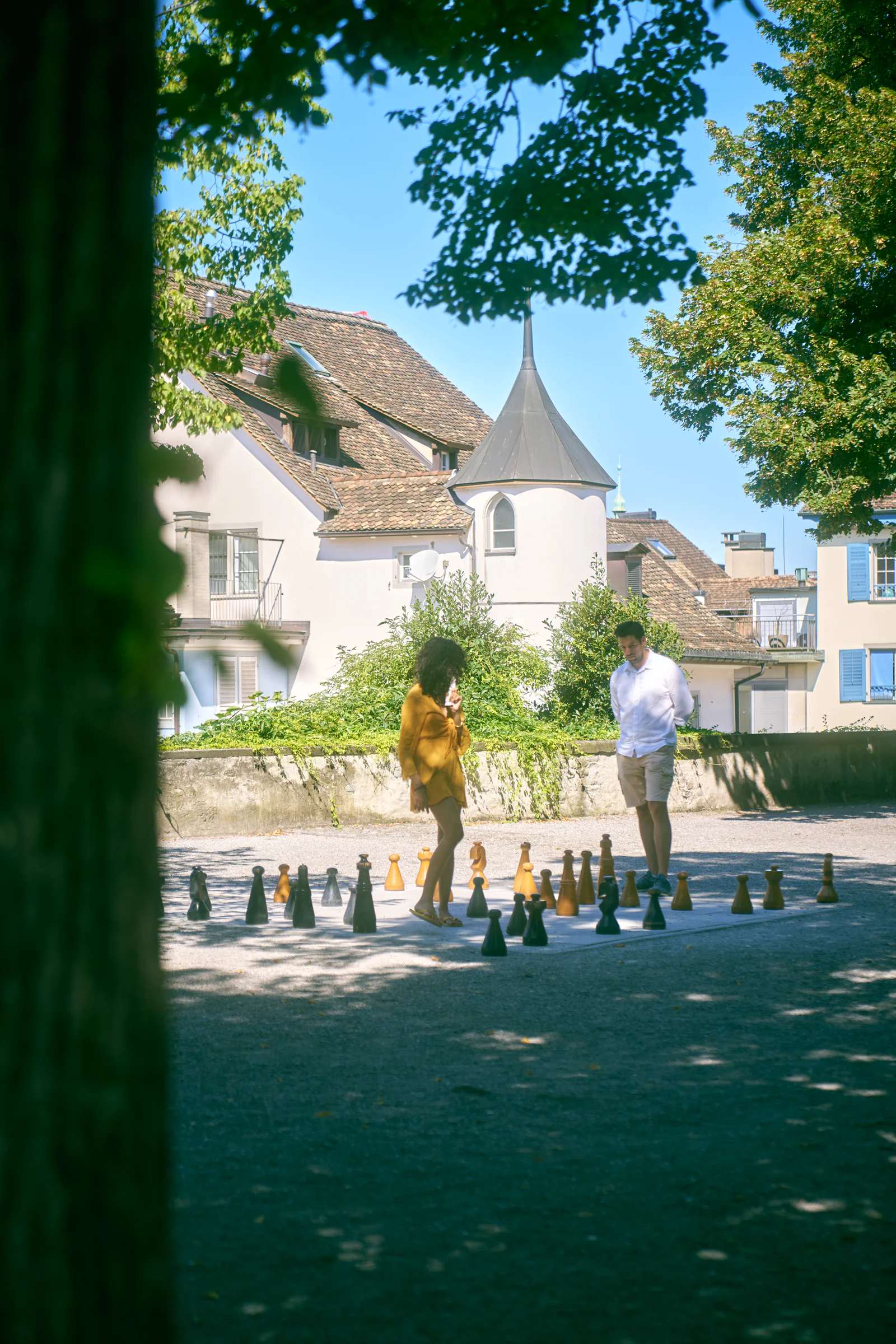 Two people playing giant chess in a park